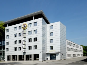 Ein modernes Hotelgebäude mit einer markanten Fassade. Es ist gut beleuchtet und befindet sich in einer städtischen Umgebung.