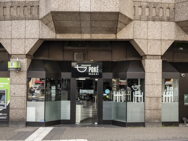 Poke Makai Außenansicht von Poke Makai im Erdgeschoss eines Gebäudes mit einer sandfarbenen Fassade und einem hohen Eingang. Oben prangt das Logo "Ernst".