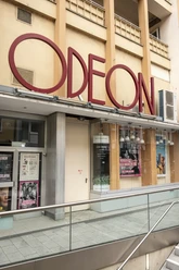 Odeon Das Odeon Kino zeigt eine stilvolle Eingangsfassade mit großen Fenstern und einem markanten rotem Schriftzug.