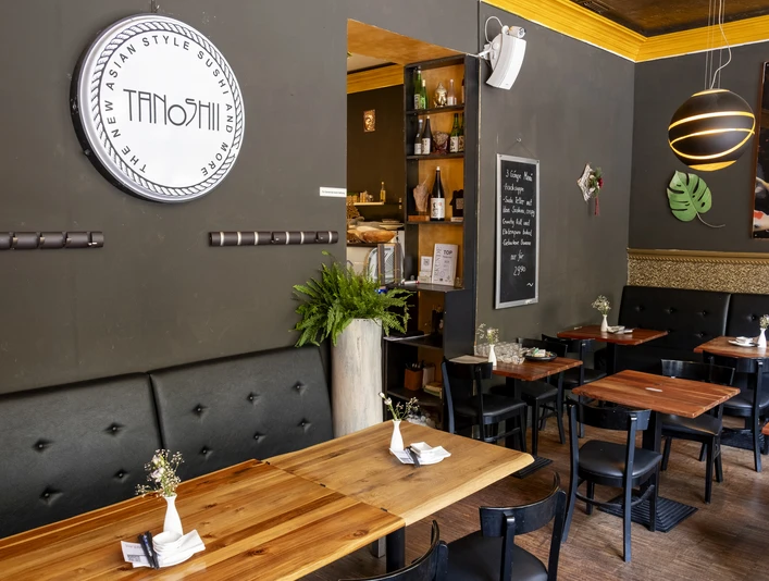 Tanoshii Innenansicht des Restaurants Tanoshii: Moderne, gemütliche Atmosphäre mit Holz- und Schwarzakzenten.Interior view of Tanoshii restaurant: a modern and cozy ambiance featuring stylish wooden elements complemented by black accents.