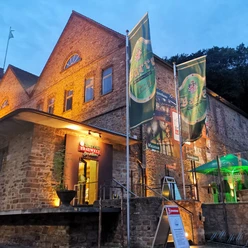 Barres Brauwelt Rote Backsteingebäude von Barre's Brauwelt mit großen grünen Brauereifahnen bei Dämmerung.