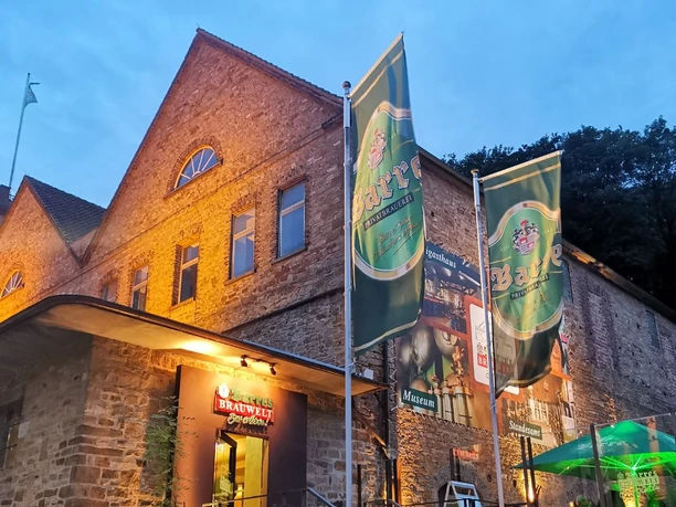 Barres Brauwelt Rote Backsteingebäude von Barre's Brauwelt mit großen grünen Brauereifahnen bei Dämmerung.