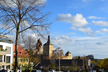 Rathaus Bensberg Ansicht von Bergisch Gladbach mit historischer Kirche und modernen Gebäuden unter blauem Himmel.