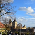 Rathaus Bensberg Ansicht von Bergisch Gladbach mit historischer Kirche und modernen Gebäuden unter blauem Himmel.