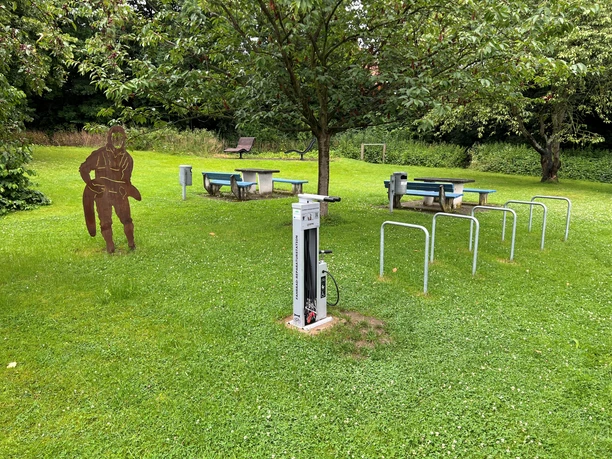 Rastplatz Petershagen Rastplatz mit überdachten Picknicktischen, Spielskulptur, Fahrradständern und grüner Umgebung in Petershagen.