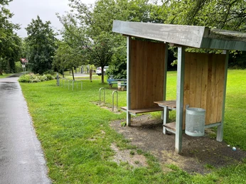 Rastplatz Petershagen Rastplatz Petershagen mit überdachter Sitzgelegenheit, Mülleimer, Fahrradständern und grüner Oase.