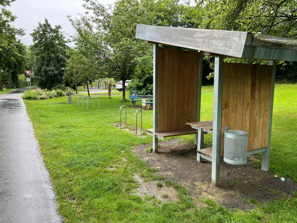 Rastplatz Petershagen Rastplatz Petershagen mit überdachter Sitzgelegenheit, Mülleimer, Fahrradständern und grüner Oase.