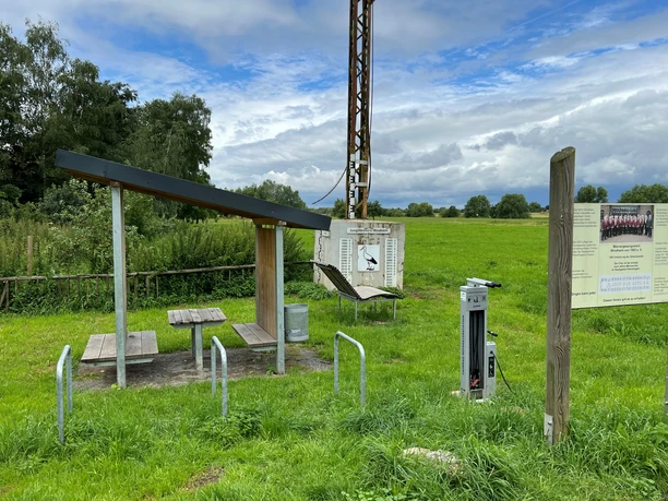 Rastplatz Windheim Rastplatz mit Überdachung und Picknicktisch inmitten einer grünen Wiese unter bewölktem Himmel.