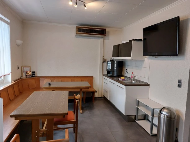 Küche mit Essbereich im Gasthof Becker in Wülfrath Essbereich und funktionale Küche im Gasthof Becker, ausgestattet mit Sitzbank und Holztischen.