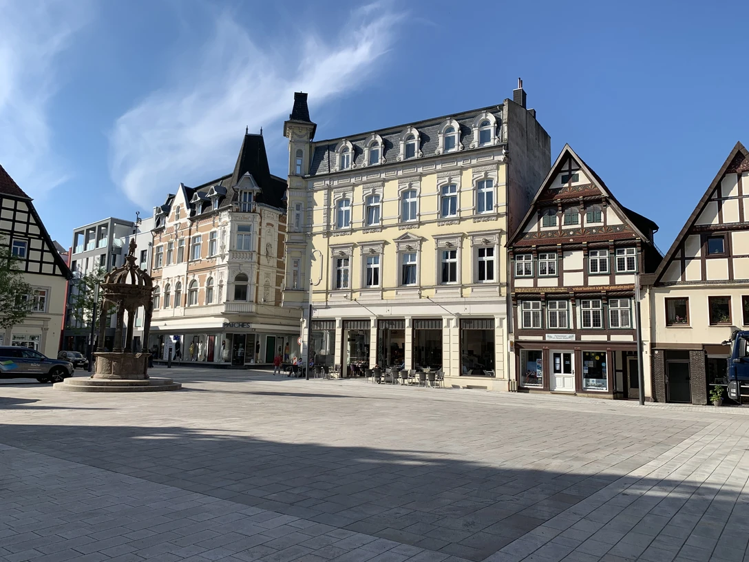 IMG_5549.JPG Historische Gebäude umrahmen einen ruhigen, gepflasterten Platz bei strahlend blauem Himmel.
