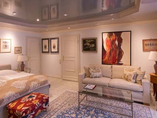 Zimmer in der Villa Mettmann Helles Zimmer in der Villa Mettmann mit Doppelbett, Sofa, Glastisch und Kunstwerken an den Wänden.