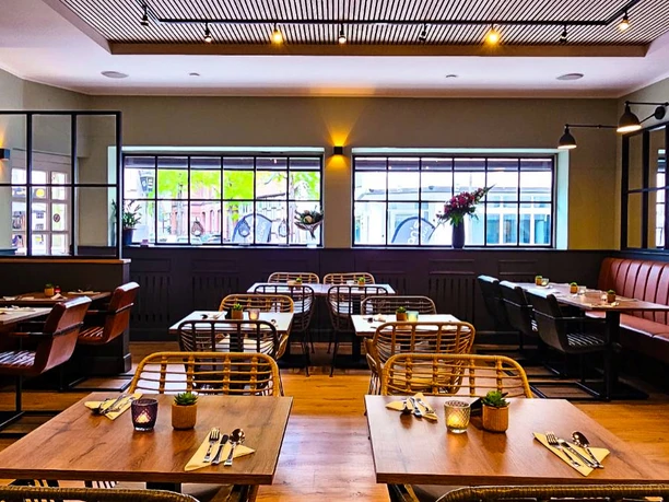 Chans Thai Kitchen Ruhiges Restaurant mit modernen Holztischen, Stühlen und großen Fenstern, die Tageslicht hereinlassen.