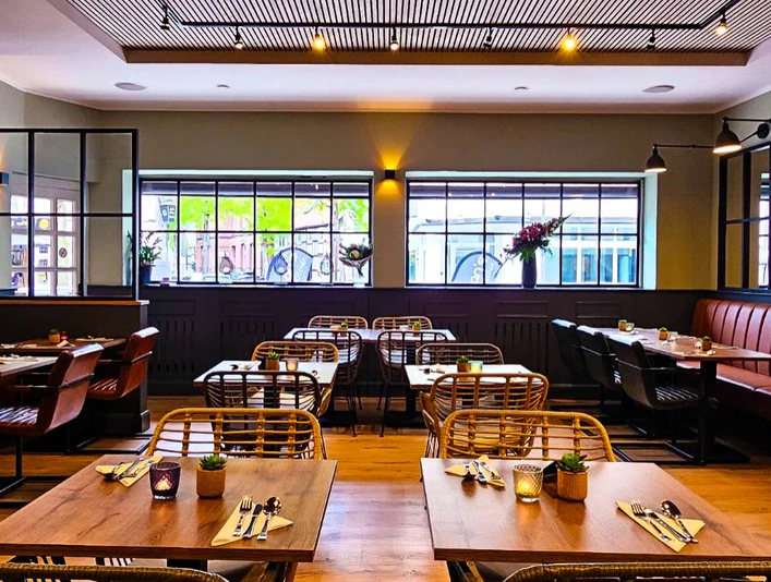 Chans Thai Kitchen Ruhiges Restaurant mit modernen Holztischen, Stühlen und großen Fenstern, die Tageslicht hereinlassen.