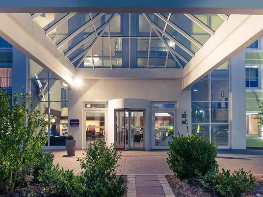 Hoteleingang zum Mercure Hotel Düsseldorf-Ratingen Eingangsbereich des Mercure Hotels mit gläsernem Vordach und einladender Beleuchtung bei Nacht.