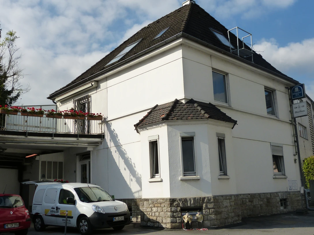 Ferienwohnung Henrys Oak "am Kolben 5" in Mettmann Ein zweistöckiges weißes Gebäude mit Satteldach und Balkon, umgeben von geparkten Fahrzeugen.