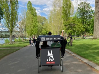 Rikolonia Eine Rikscha fährt durch einen grünen Park in Köln, gehüllt in ein klares Frühlingslicht.A rickshaw drives through a green park in Cologne, bathed in clear spring light.