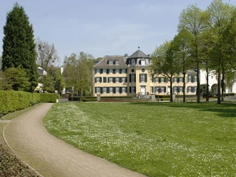 Cromford Park mit Blick auf das Herrenhaus Cromford Großzügige Rasenfläche führt zum historischen Herrenhaus Cromford, umgeben von Bäumen im Frühling.