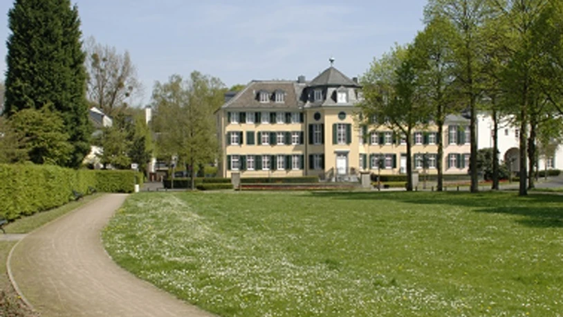 Cromford Park mit Blick auf das Herrenhaus Cromford Großzügige Rasenfläche führt zum historischen Herrenhaus Cromford, umgeben von Bäumen im Frühling.