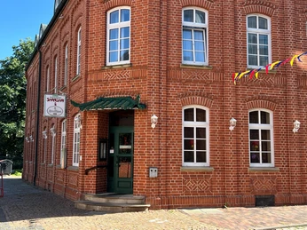 Das Bild zeigt ein traditionelles Backsteingebäude mit einem Restaurant im Erdgeschoss und bunter Dekoration.