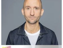 Markus Barth lächelt leicht in die Kamera, vor grauem Hintergrund, in Jeansjacke und weißem Shirt.