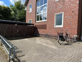 Fahrradstellplatz.jpg Ein sauberer Fahrradstellplatz vor einem Backsteingebäude mit verschiedenen Fahrradständern.