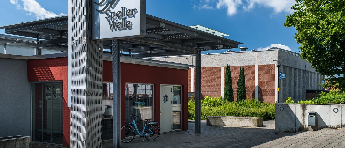 Speller Welle Eingangsbereich der Schwimmhalle Speller Welle mit moderner Beschilderung und blauem Himmel.