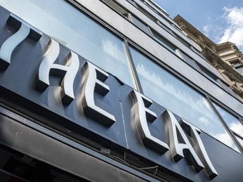The Eat Das Bild zeigt ein modernes, mehrstöckiges Gebäude mit verspiegelten Glasfenstern und der großen, stilisierten Schrift "THE EAT" auf einem schwarzen Schild an der Fassade. The image shows a modern, multi-story building with mirrored glass windows and bold, stylized lettering reading "THE EAT" displayed on a black sign on the facade.