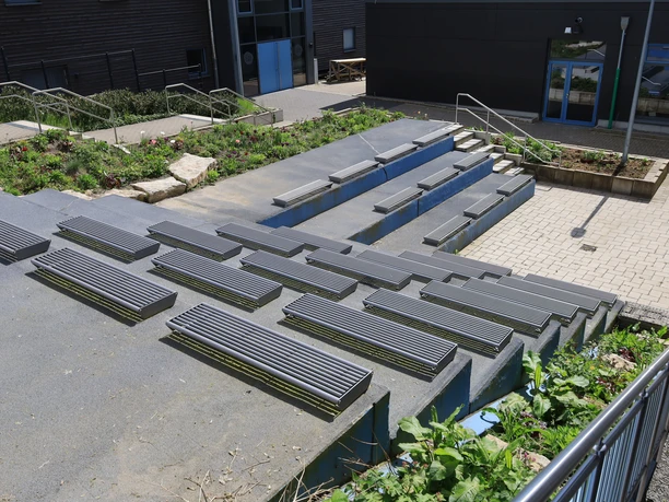 Klima-Campus Innenhof Treppenförmig angeordnete Sitzgelegenheiten im Innenhof eines modernen Campusgebäudes bei sonnigem Wetter.