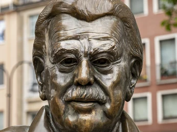 Willy Millowitsch Denkmal Das Bild zeigt das Willy Millowitsch Denkmal in Köln. Die Bronzestatue ist eine Hommage an den bekannten deutschen Volksschauspieler Willy Millowitsch. Die Skulptur stellt ihn lebensecht dar, mit einem markanten Schnurrbart und einem freundlichen Gesichtsausdruck.The picture shows the Willy Millowitsch monument in Cologne. The bronze statue is a tribute to the well-known German folk actor Willy Millowitsch. The sculpture depicts him lifelike, with a distinctive moustache and a friendly facial expression.