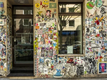 Belgisches Viertel Die Hausfassade im Belgischen Viertel Kölns ist mit vielseitigen bunten Aufklebern und Graffiti verziert.The façade of the building in Cologne's Belgian Quarter is decorated with colourful stickers and graffiti.