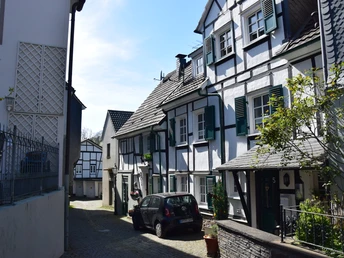 Ründeroth Fachwerkhäuser in kleiner gepflasterter Gasse, mit hochliegenden Fenstern und grünen Fensterläden.