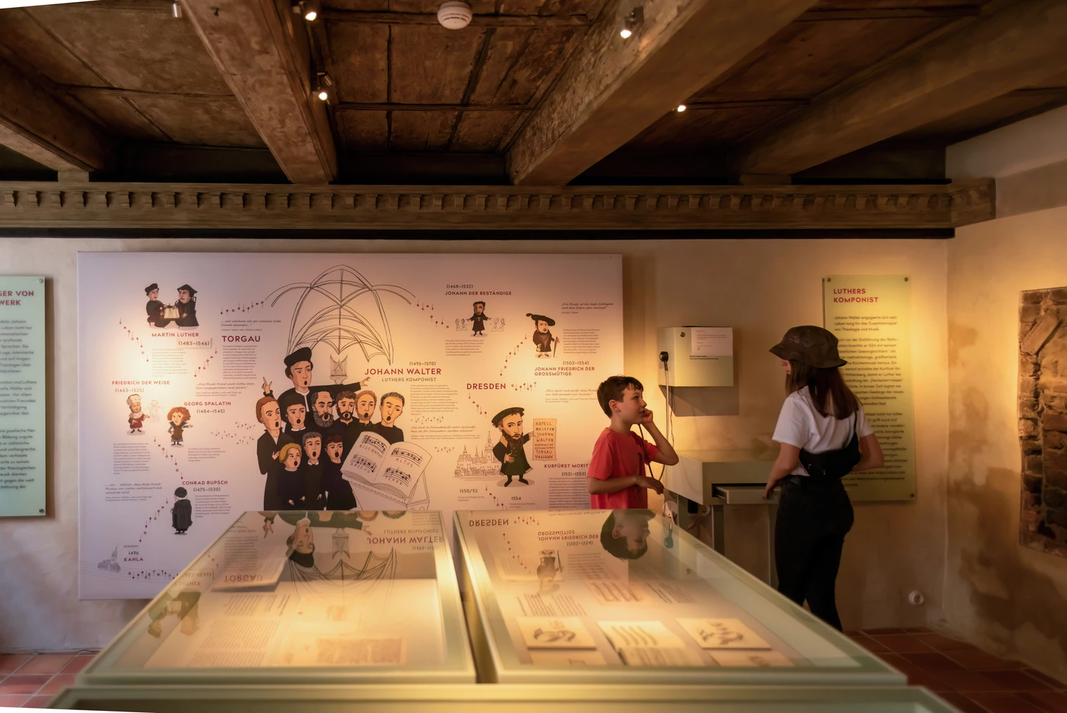 torgau-im-priesterhaus-des-georg-spalatin-foto-dirk-brzoska-de-noise-aI-low-light.jpg Ausstellungsraum mit interaktiver Wand und Besuchern im Priesterhaus von Georg Spalatin in Torgau.