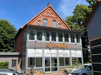 KreativWerkstatt am Wall Backstein-Gebäude mit moderner Glasfassade und Oberlichtfenstern; KreativWerkstatt-Schriftzug.