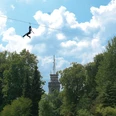 Seilbahn mit Bismarckturm im Waldkletterpark Velbert-Langenberg.jpg Eine Person schwebt mit einer Seilbahn über Baumwipfel vor dem Bismarckturm im Kletterpark.