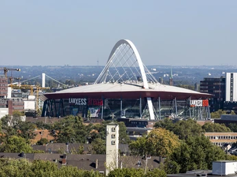 Lanxess Arena Lanxess Arena, ein riesiger roter Kuppelbau mit markantem weißen Bogenträger in Köln.Lanxess Arena, a huge red domed building with a striking white arched girder in Cologne.