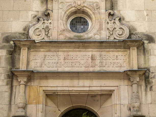 Luther Kirche Auf dem Bild ist das barocke Eingangstor der Lutherkirche zu sehen. Das Tor ist elegant verziert und besteht aus Sandstein. Über dem Torbogen befindet sich eine runde Fensteröffnung.