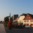 Das Hotel & Restaurant Zum Vater Rhein in der Abendsonne, Monheim am Rhein Gastronomie und Hotellerie am Rhein, im Abendlicht von Monheim gelegen mit roten Blumen im Vordergrund.