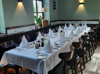 "Grüner Saal" im Restaurant "Die Krone Homberg" Ein mit edlem Geschirr gedeckter Tisch in einem elegant ausgeleuchteten Raum mit grünen Wänden.