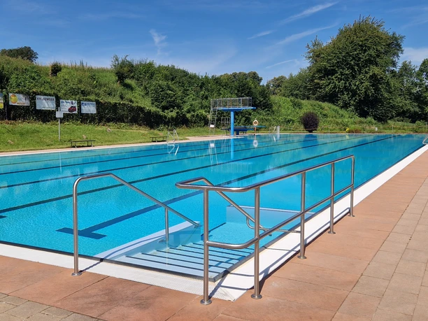 Waldfreibad Valdorf Schwimmer Ein großes, längliches Schwimmbecken von Waldfreibad Valdorf bei strahlendem Sonnenschein.