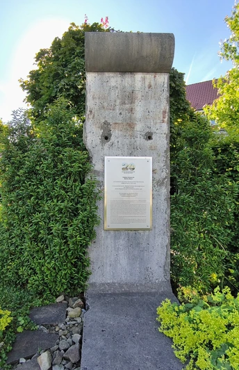 Ein Stück der Berliner Mauer steht umgeben von grüner Vegetation in einem Garten in Hövelhof.