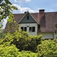 Forsthaus Hövelhof Sattes Grün umgibt das Forsthaus Hövelhof mit einem Giebel und roten Ziegeldach unter blauem Himmel.