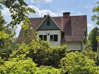 Forsthaus Hövelhof Sattes Grün umgibt das Forsthaus Hövelhof mit einem Giebel und roten Ziegeldach unter blauem Himmel.