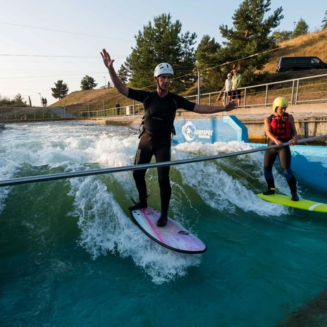 Dwie osoby stoją na deskach surfingowych w Markkleeberg Canoe Park i próbują swoich sił w surfingu na falach, sporty wodne, biała woda, aktywność rekreacyjna