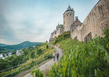 Wandernde an der Burg Altena Zwei Wandernde auf dem Sauerland-Höhenflug unterhalb der Burg Altena