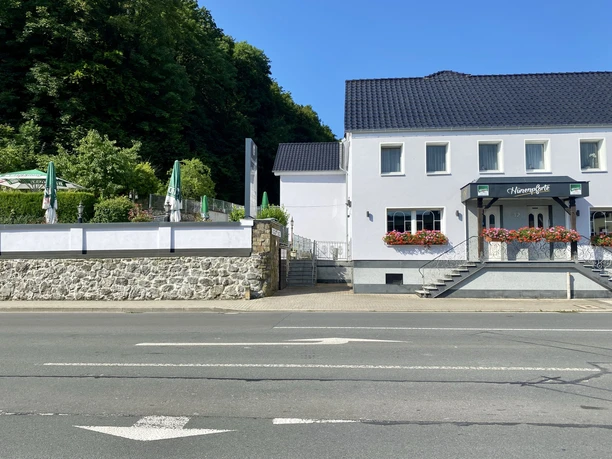 Restaurant Hünenpforte in einer weißen Villa mit blumenverzierter Terrasse und umgebenden Grünflächen.