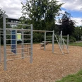 Calisthenics-centrum | Büren Outdoor-Sportplatz mit Klettergerüsten auf Rindenmulch, umgeben von Bäumen und Rasenfläche.