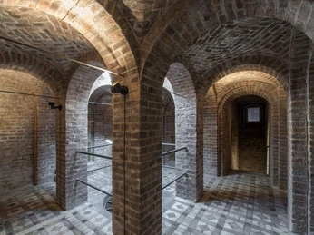 Römergrab Weiden Das Bild zeigt ein antikes Gewölbe mit gemauerten Rundbögen und einem Boden im Mosaikdesign.The picture shows an antique vault with brick arches and a mosaic floor.