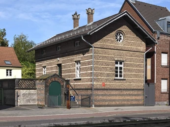 Roman grave Weiden Das Bild zeigt ein altes, gut erhaltenes Backsteinhaus mit schmalen Fenstern und gemauertem Schornstein. Der Eingangsbereich ist durch einen gewölbten Torbogen gekennzeichnet, der in einem ebenfalls aus Backstein gebauten Flügel mündet. The picture shows an old, well-preserved brick house with narrow windows and a brick chimney. The entrance area is characterized by a vaulted archway that leads into a wing also made of brick.