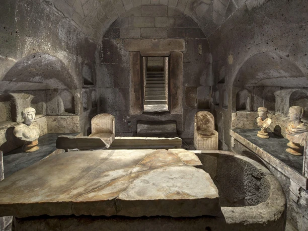 Römergrab Weiden Ein eindrucksvoller römischer Grabraum mit steinerner Decke, Skulpturen und steinernen Bänken.