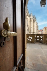 Rathaus Osnabrück Tür mit dekorativem Türgriff neben steinernem Balkon und historischen Gebäuden im Hintergrund.